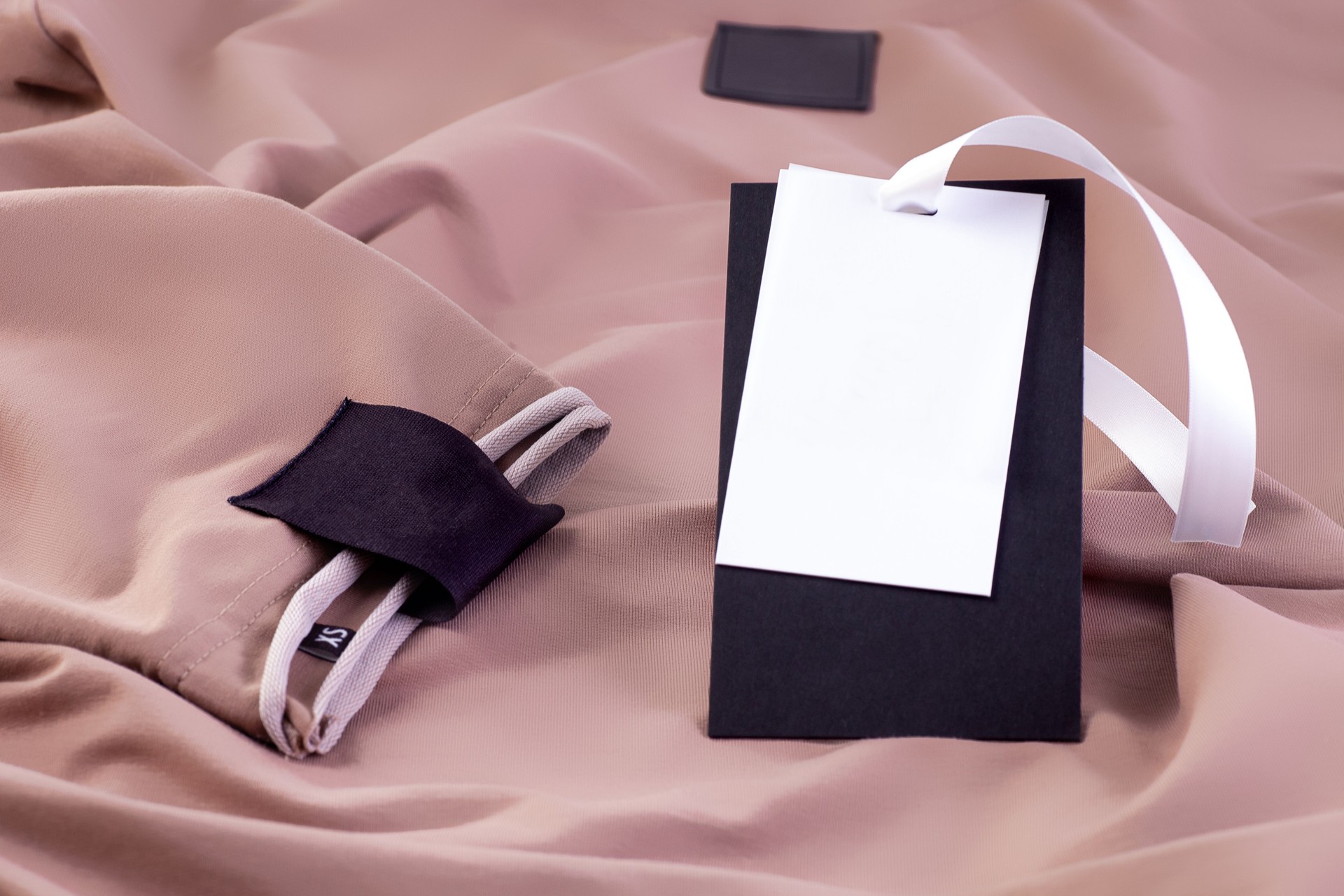 macro mock up fabric empty black patch for the brand logo on the sleeve and a paper label on a white ribbon on beige clothing
