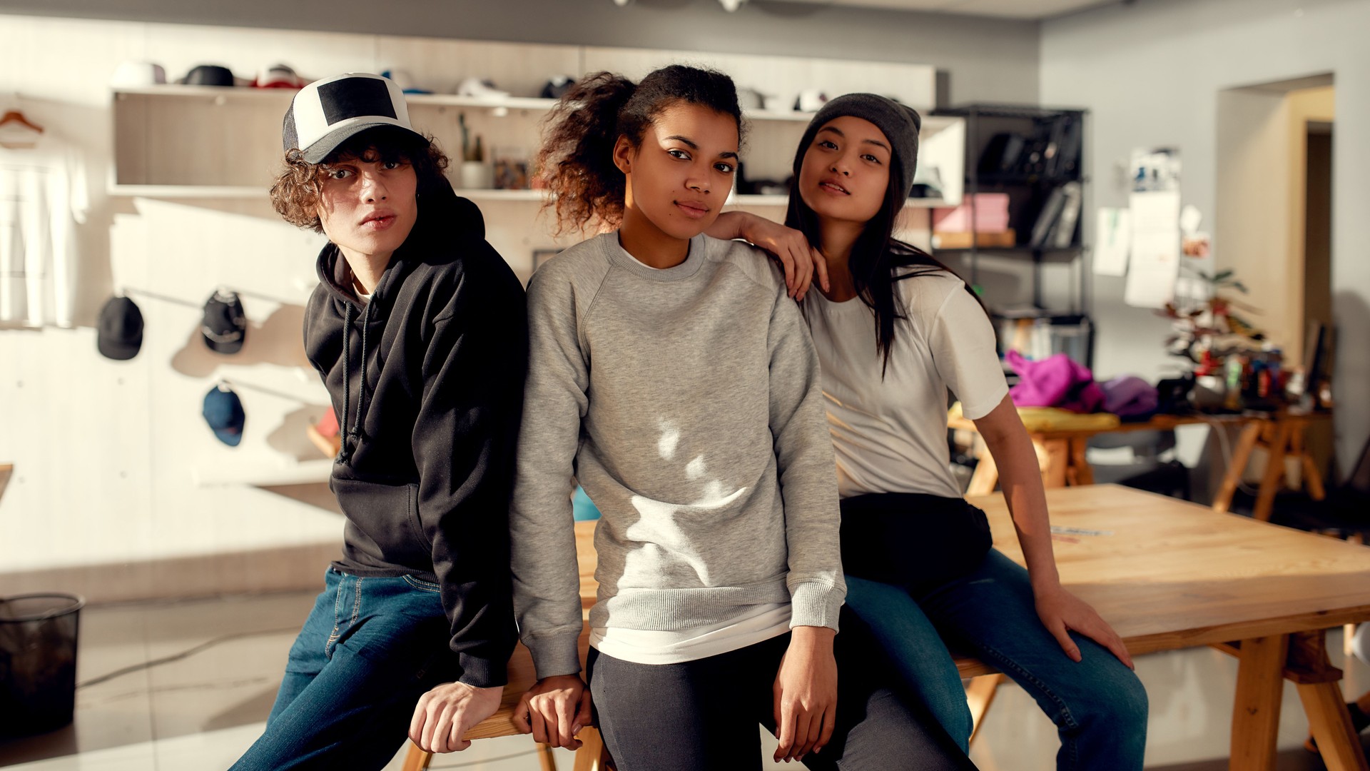 Love your brand. Creative team looking at camera while posing in custom apparel. Young man and women working at custom T-shirt, clothing printing company